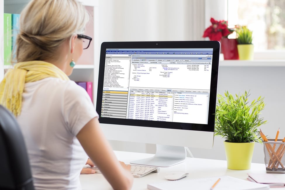 woman at desk looking at computer using GoldMine CRM