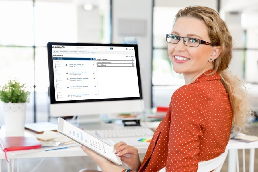 Woman in glasses at desk using GoldMine CRM