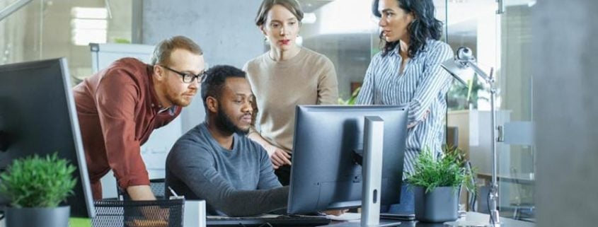 Forbes article business meeting four people looking at a computer